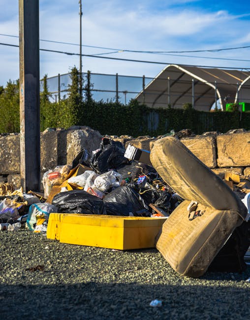 An extensive aerial view of a large landfill site filled with a dense accumulation of mixed waste materials. The waste consists primarily of plastics, including bottles, bags, and fragments of various